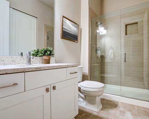 Bathroom with glass-enclosed shower, beige tile surround, and white vanity