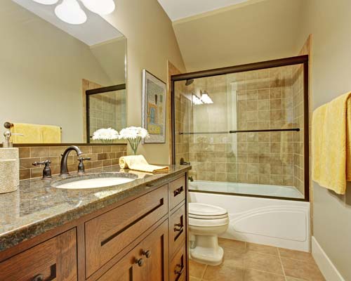 Bathroom with tub-shower combo, tan tile surround, glass sliding doors, and oak vanity
