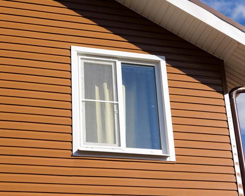 White vinyl window with grids installed on tan vinyl siding